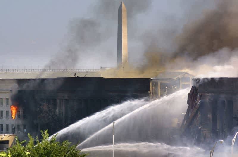 Пожарные проливают водой и пеной обрушившуюся часть здания Пентагона.